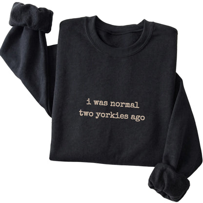 Black I Was Normal Two Yorkies Ago sweatshirt folded to show the printed design