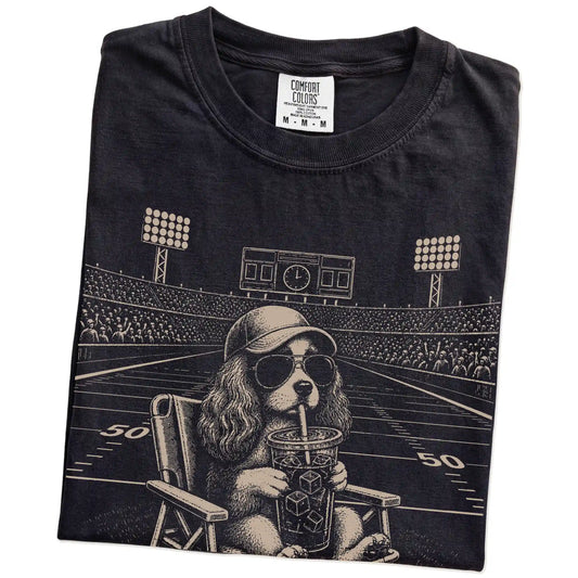 Folded Black Comfort Colors® T-shirt showing Cavalier King Charles Spaniel claiming the football field with “I Live Here Now”