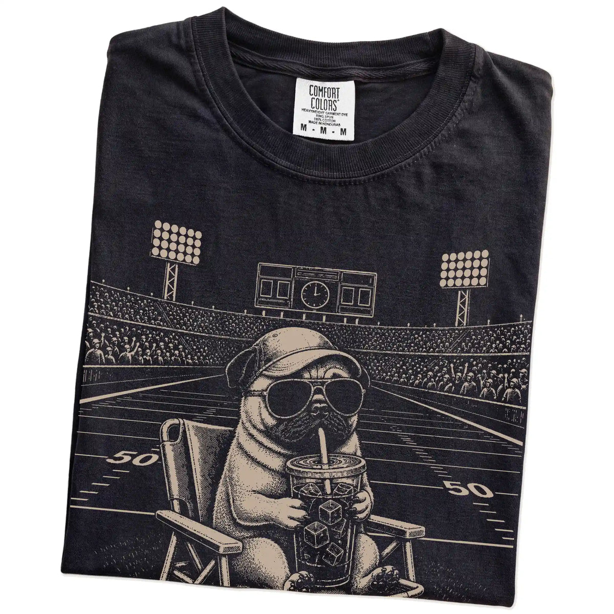 Folded Black Comfort Colors® T-shirt showing Pug claiming the football field with “I Live Here Now” lettering