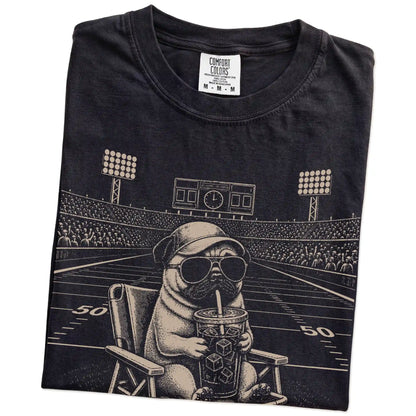 Folded Black Comfort Colors® T-shirt showing Pug claiming the football field with “I Live Here Now” lettering