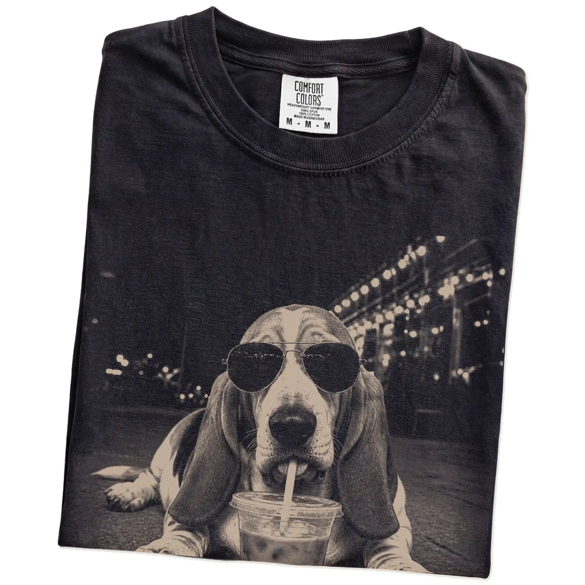 Folded Black Comfort Colors® T-shirt showing Basset Hound with iced coffee in a retro grunge design