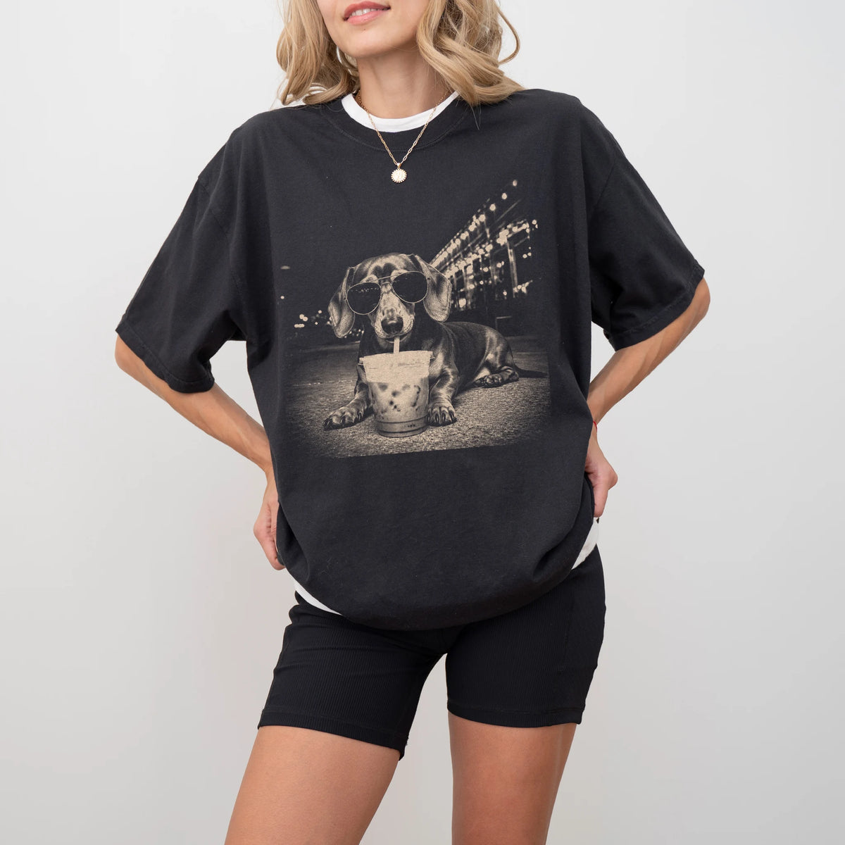 Model wearing a Black Comfort Colors® T-shirt featuring Dachshund with iced coffee in a retro grunge design
