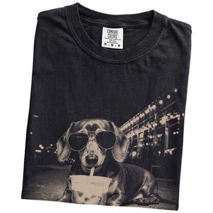 Folded Black Comfort Colors® T-shirt showing Dachshund with iced coffee in a retro grunge design