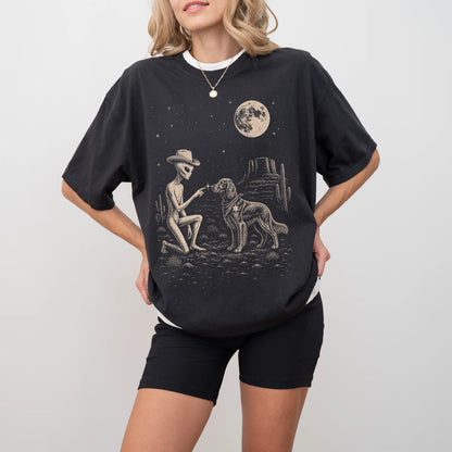 Model wearing a Black Comfort Colors® T-shirt with cowboy alien fist-bumping a irish setter beneath the moon