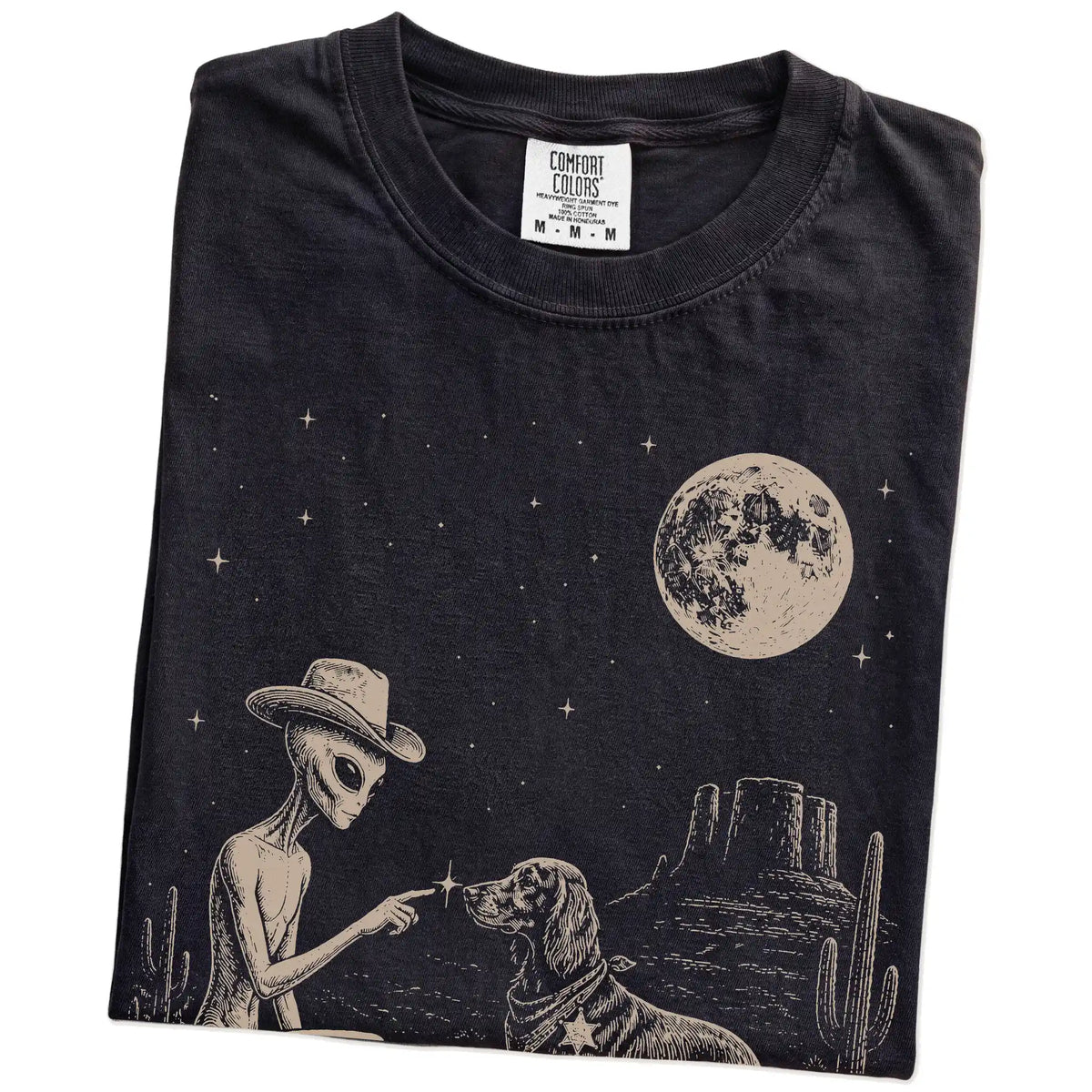 Folded Black Comfort Colors® T-shirt showing cowboy alien fist-bumping a irish setter beneath the moon