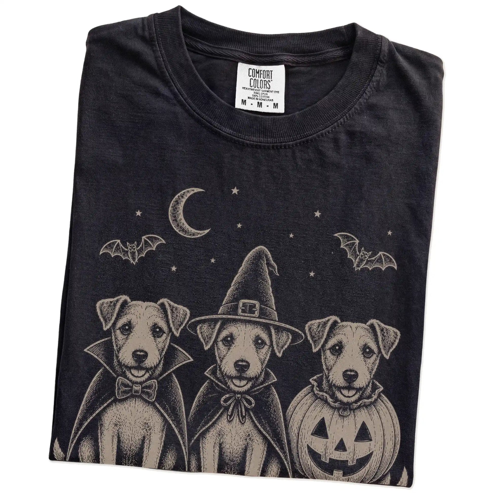 Folded Black Comfort Colors® T-shirt showing three Jack Russell dogs dressed for Halloween beneath bats and a crescent moon