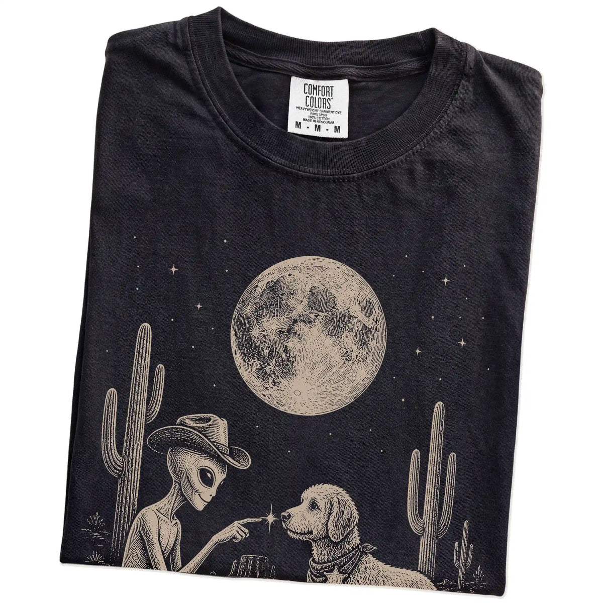 Folded Black Comfort Colors® T-shirt showing cowboy alien fist-bumping a labradoodle beneath the moon