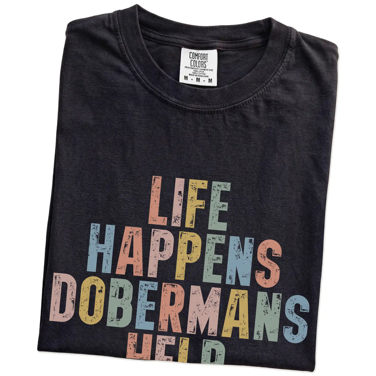 Folded Black Comfort Colors® T-shirt showing Doberman making hard days better with “Life Happens, Dogs Help” lettering