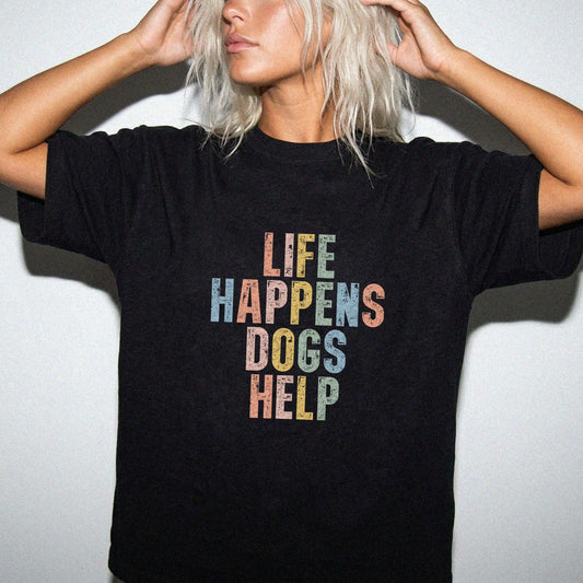 Model wearing a Black Comfort Colors® T-shirt featuring dogs making hard days better with “Life Happens, Dogs Help” lettering