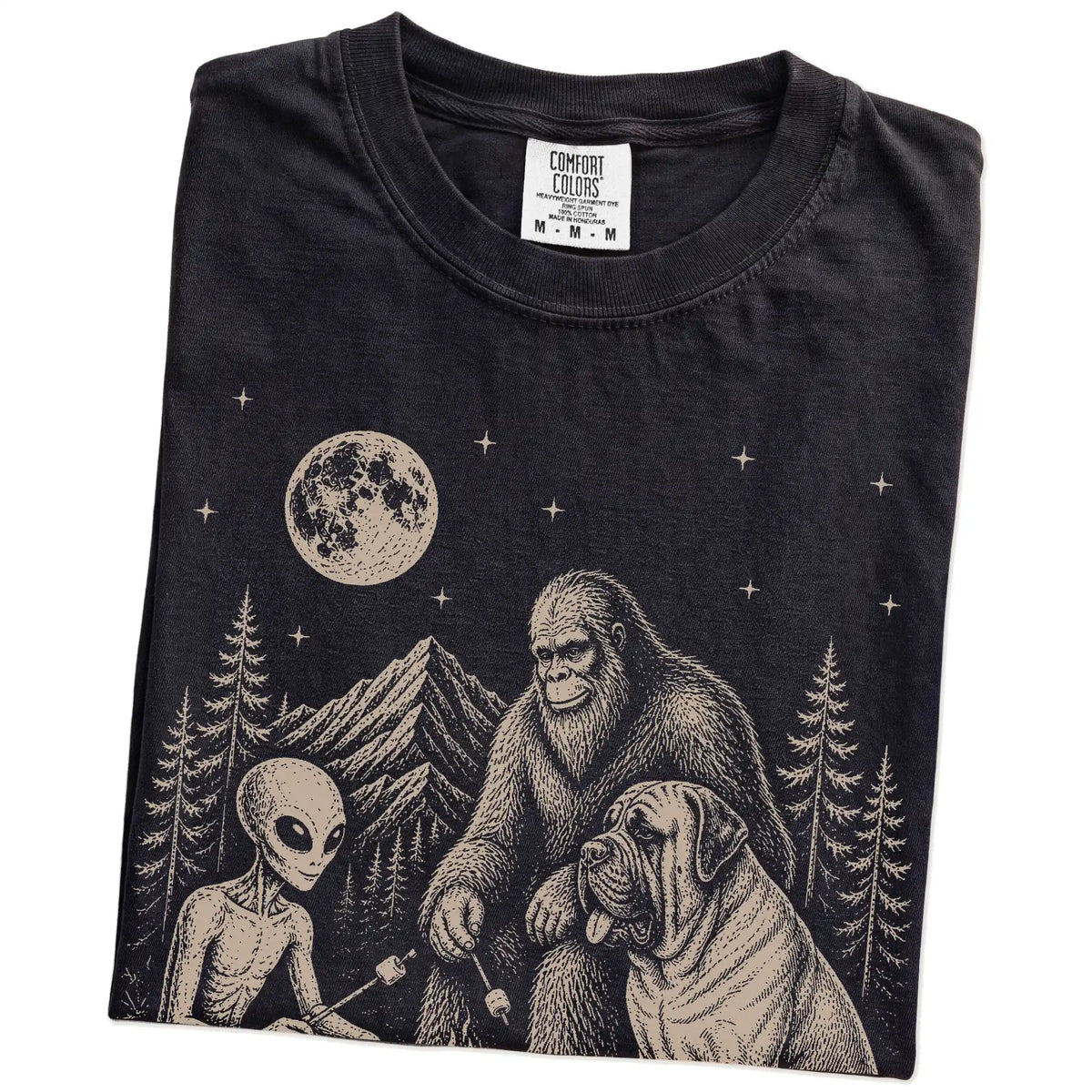 Folded Black Comfort Colors® T-shirt showing Mastiff camping with Bigfoot and an alien