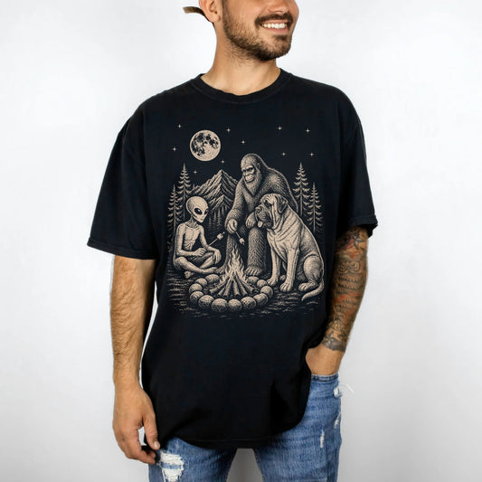Model wearing a Black Comfort Colors® T-shirt showing Mastiff camping with Bigfoot and an alien