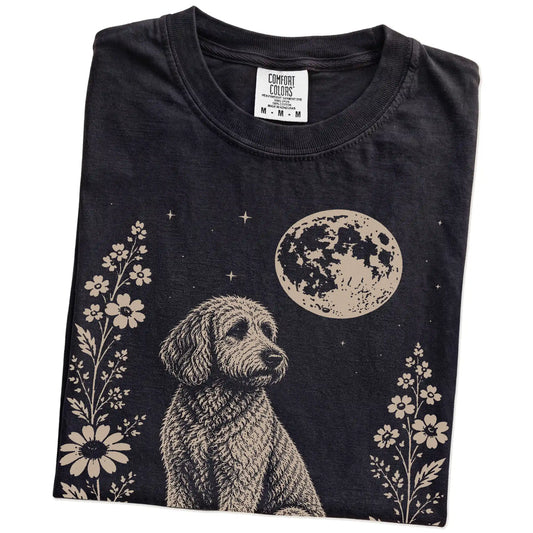 Folded Black Comfort Colors® T-shirt showing Labradoodle framed by flowers beneath the moon