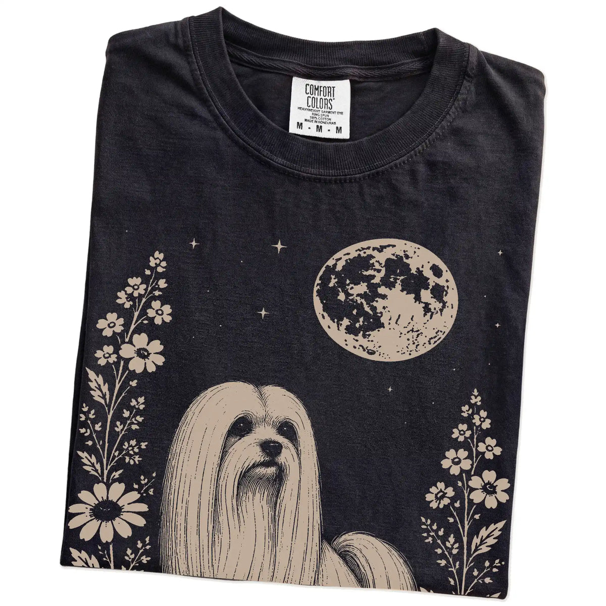Folded Black Comfort Colors® T-shirt showing Maltese framed by flowers beneath the moon