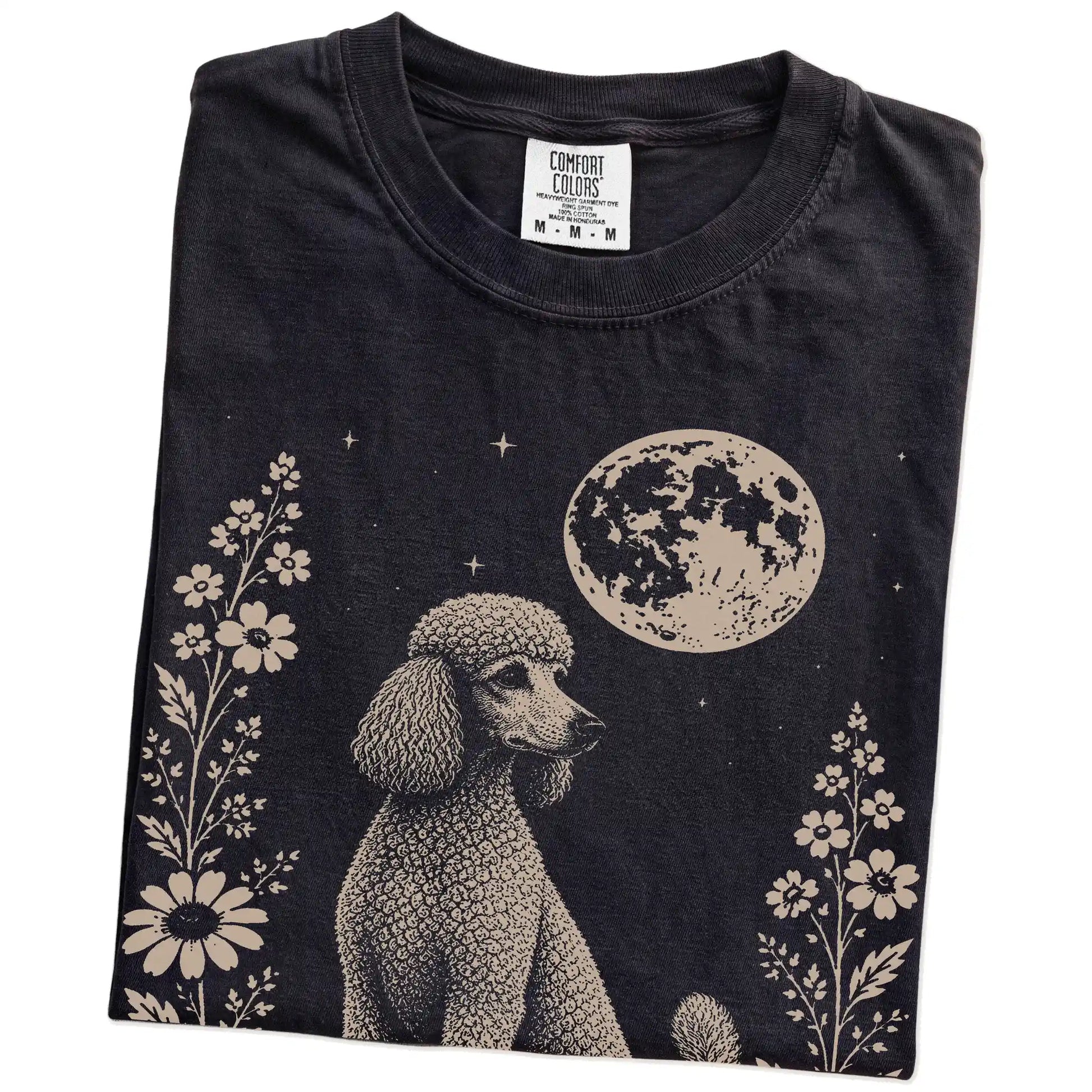 Folded Black Comfort Colors® T-shirt showing Poodle framed by flowers beneath the moon