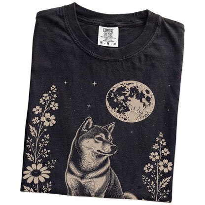 Folded Black Comfort Colors® T-shirt showing Shiba Inu framed by flowers beneath the moon