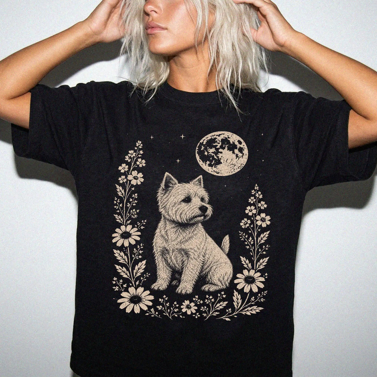 Model wearing a Black Comfort Colors® T-shirt featuring Westie framed by flowers beneath the moon