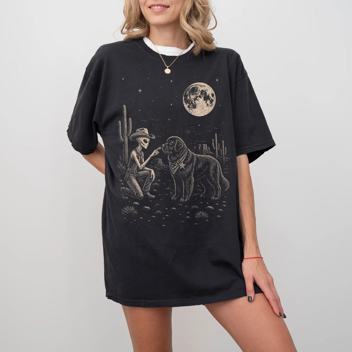 Model wearing a Black Comfort Colors® T-shirt with cowboy alien fist-bumping a newfie beneath the moon