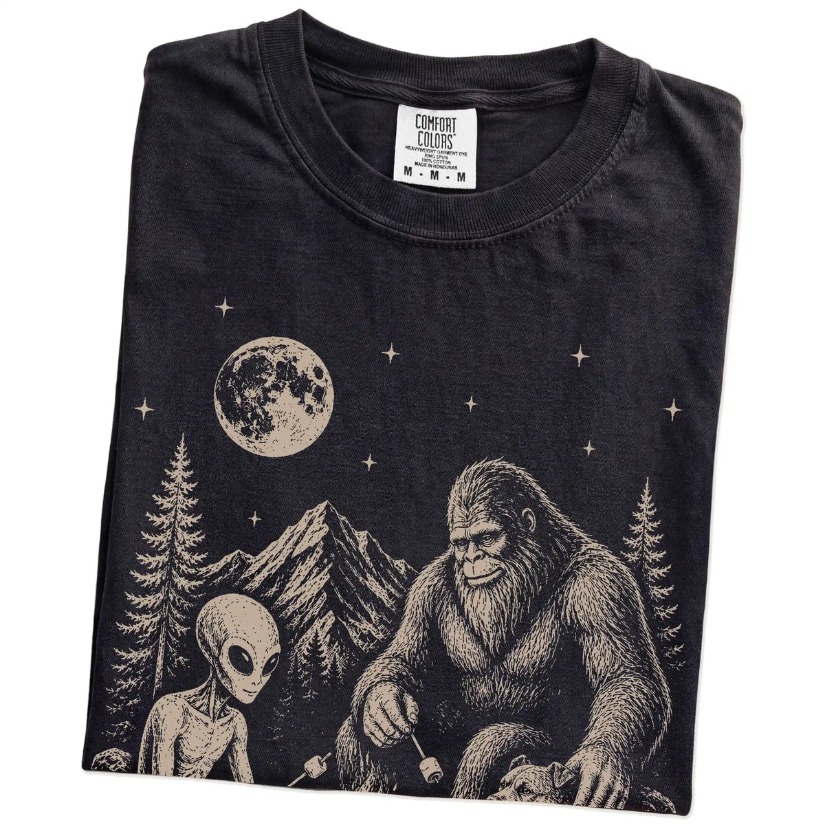 Folded Black Comfort Colors® T-shirt showing Pitbull camping with Bigfoot and an alien