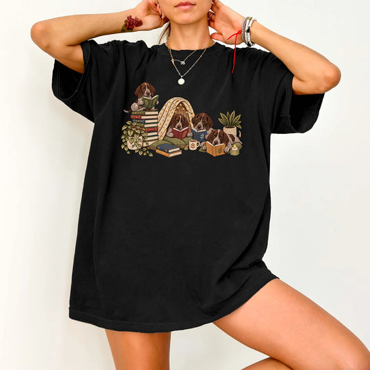 Pointer puppies reading books in a cozy blanket fort on a Black T-shirt worn by a model