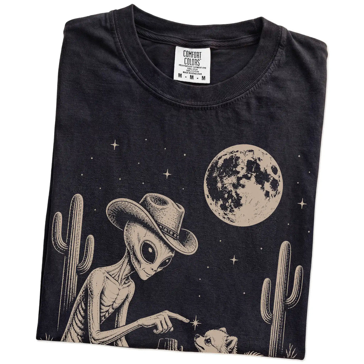 Folded Black Comfort Colors® T-shirt showing cowboy alien fist-bumping a pomeranian beneath the moon