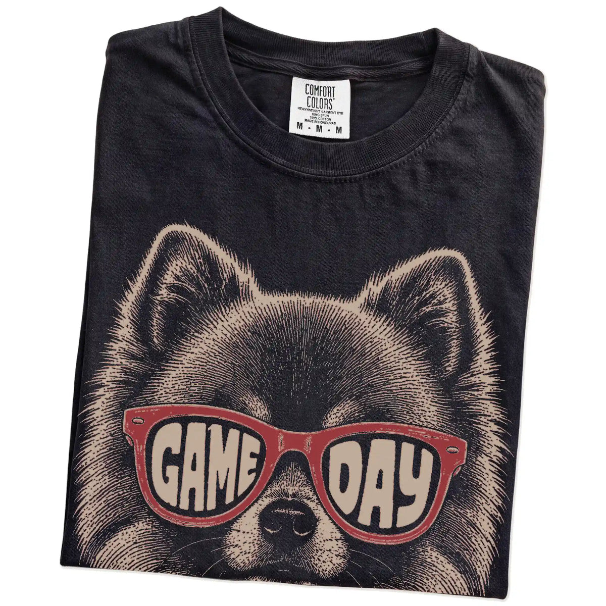 Folded Black Comfort Colors® T-shirt showing pomeranian wearing red game day sunglasses