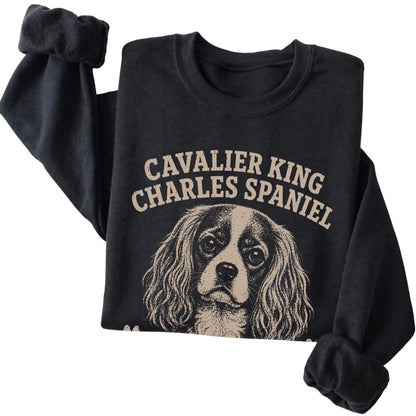Black crewneck sweatshirt featuring Professionally Affectionate - Cavalier King Charles Spaniel, folded presentation