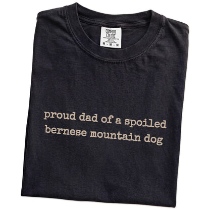 Folded Black Comfort Colors® T-shirt showing proud dad of a spoiled bernese mountain dog lettering