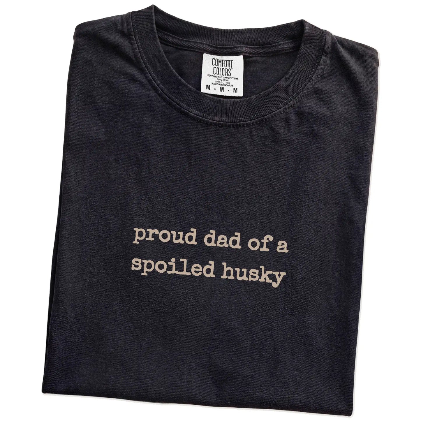 Folded Black Comfort Colors® T-shirt showing proud dad of a spoiled husky lettering