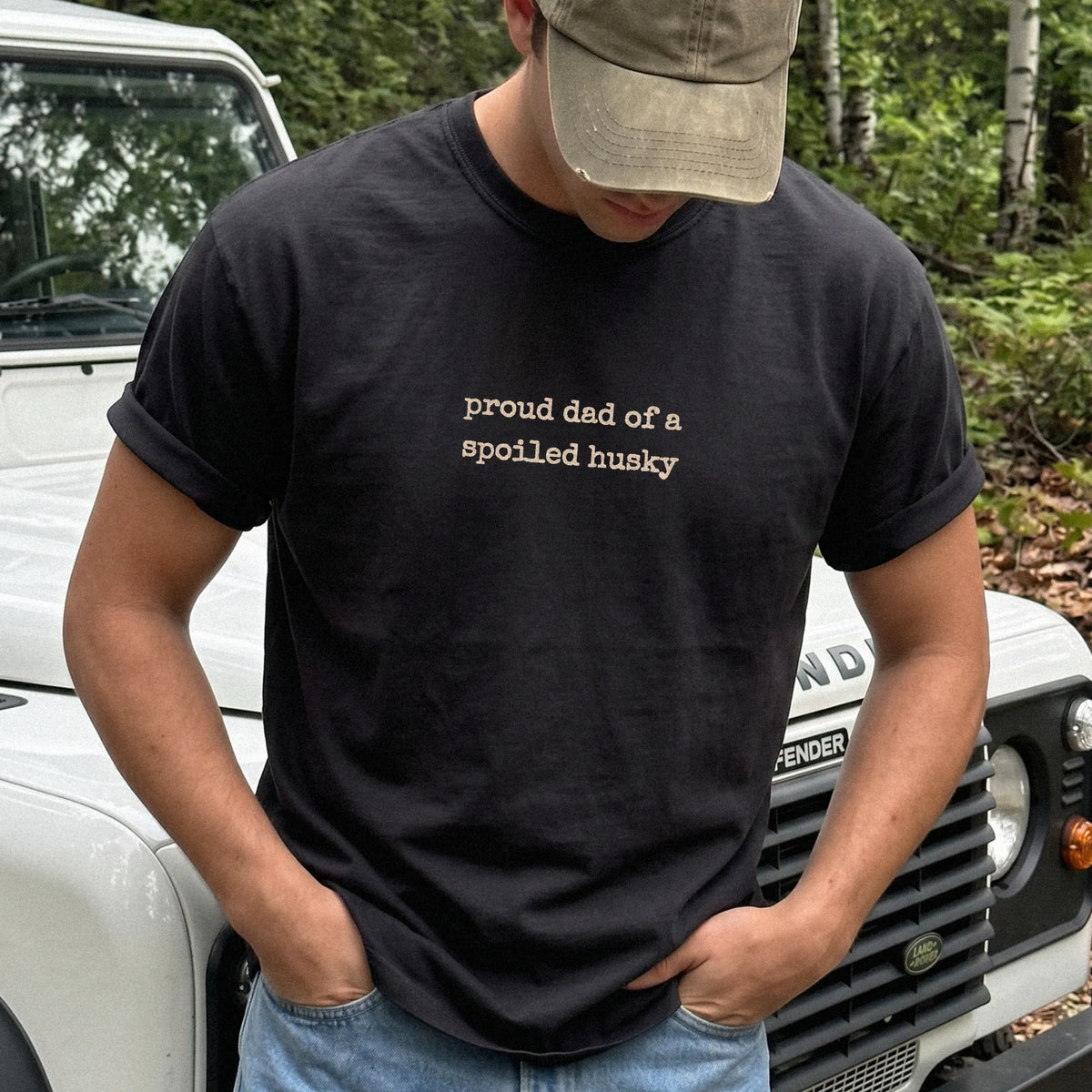 Model wearing a Black Comfort Colors® T-shirt with proud dad of a spoiled husky lettering