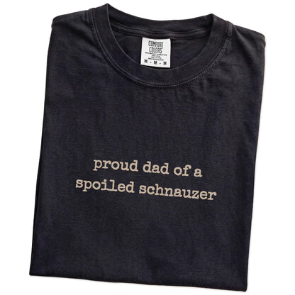 Folded Black Comfort Colors® T-shirt showing proud dad of a spoiled schnauzer lettering