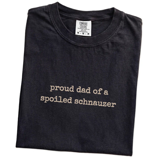 Folded Black Comfort Colors® T-shirt showing proud dad of a spoiled schnauzer lettering