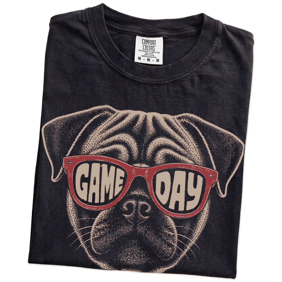 Folded Black Comfort Colors® T-shirt showing pug wearing red game day sunglasses