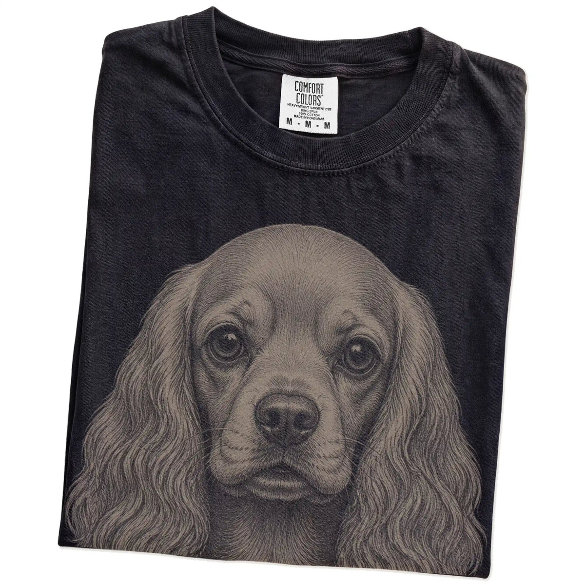 Folded Black Comfort Colors® T-shirt showing a realistic drawing of a Cocker Spaniel