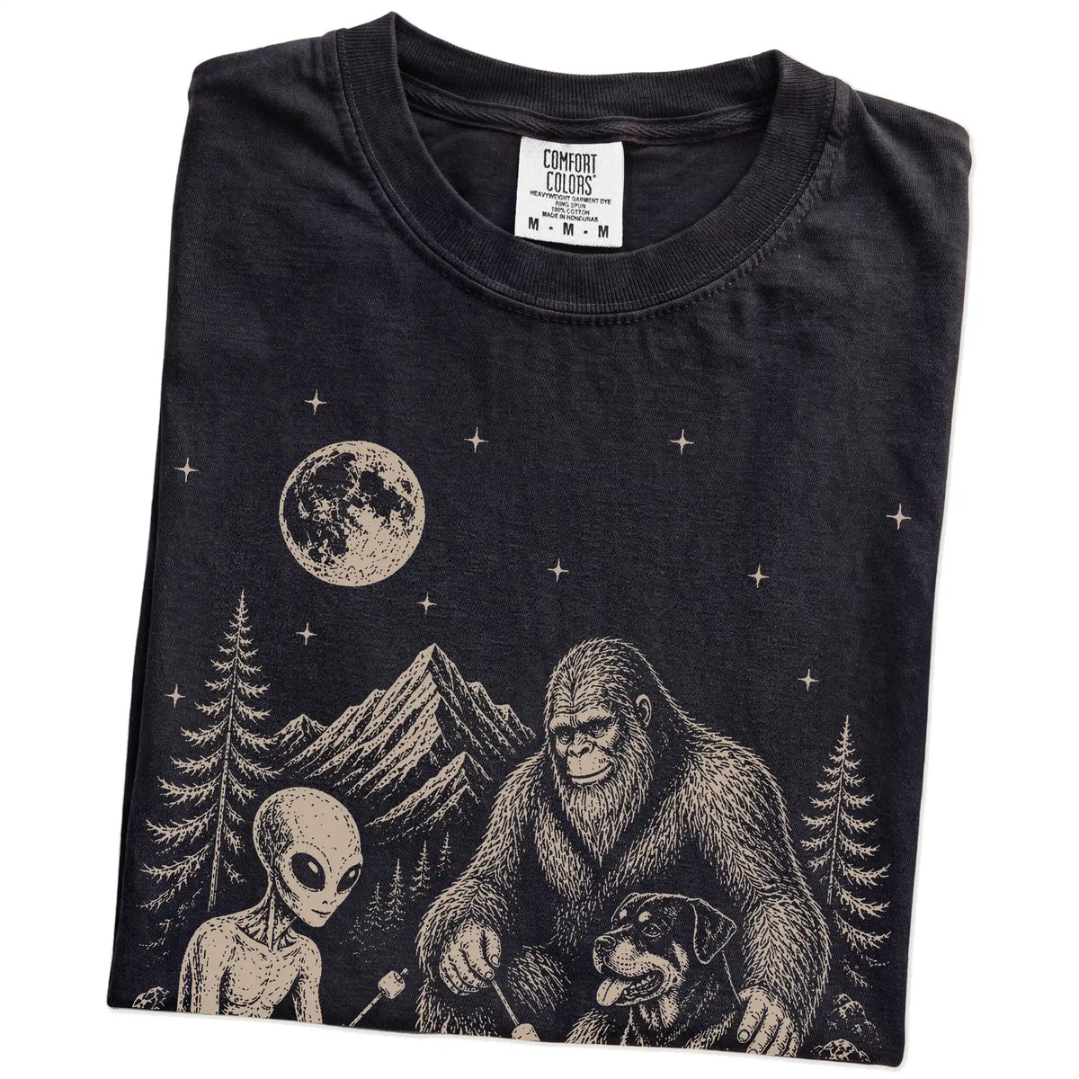 Folded Black Comfort Colors® T-shirt showing Rottweiler camping with Bigfoot and an alien