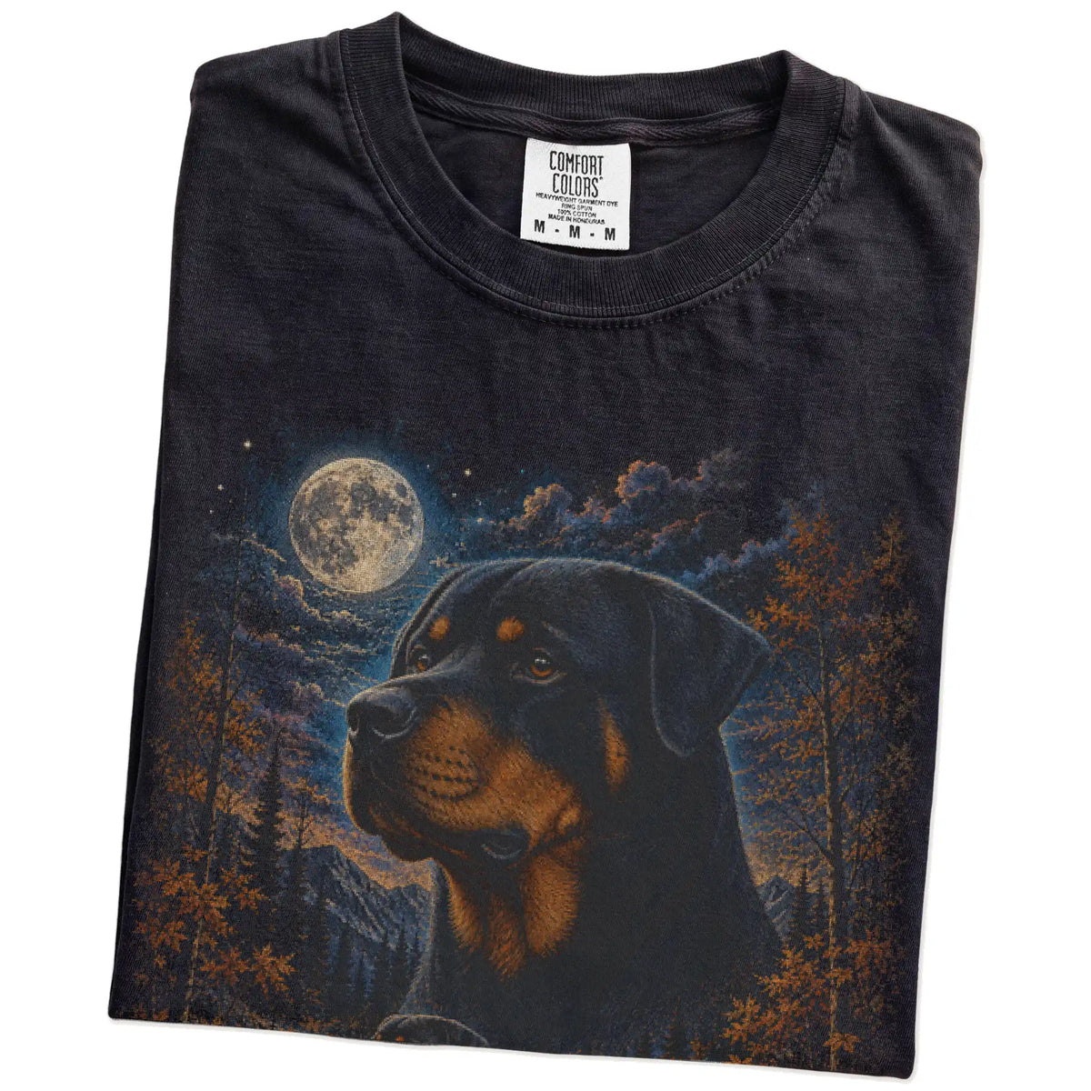 Folded Black Comfort Colors® t-shirt showing Rottweiler in a fall forest graphic