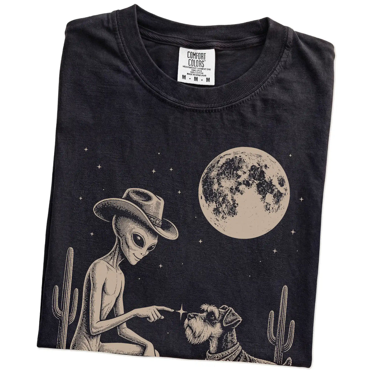 Folded Black Comfort Colors® T-shirt showing cowboy alien fist-bumping a schnauzer beneath the moon