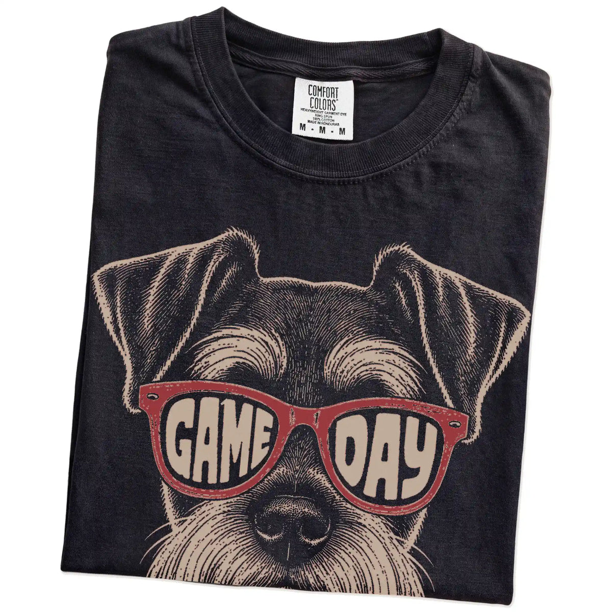 Folded Black Comfort Colors® T-shirt showing schnauzer wearing red game day sunglasses