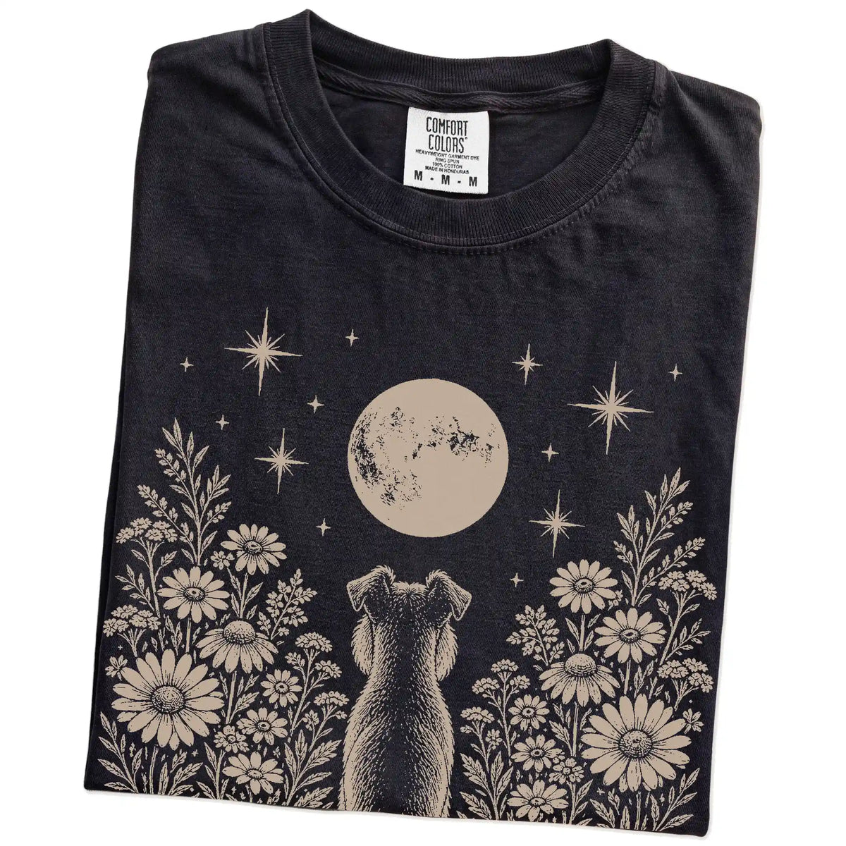Folded Black Comfort Colors® T-shirt showing Schnauzer beneath a wildflower moon