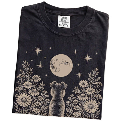 Folded Black Comfort Colors® T-shirt showing Schnauzer beneath a wildflower moon