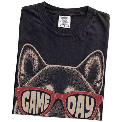 Folded Black Comfort Colors® T-shirt showing shiba inu wearing red game day sunglasses