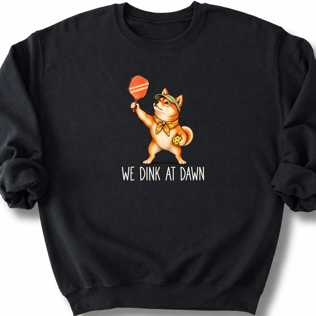 Shiba Inu with a pickleball paddle and ball on a Black Gildan® sweatshirt with We Dink at Dawn text