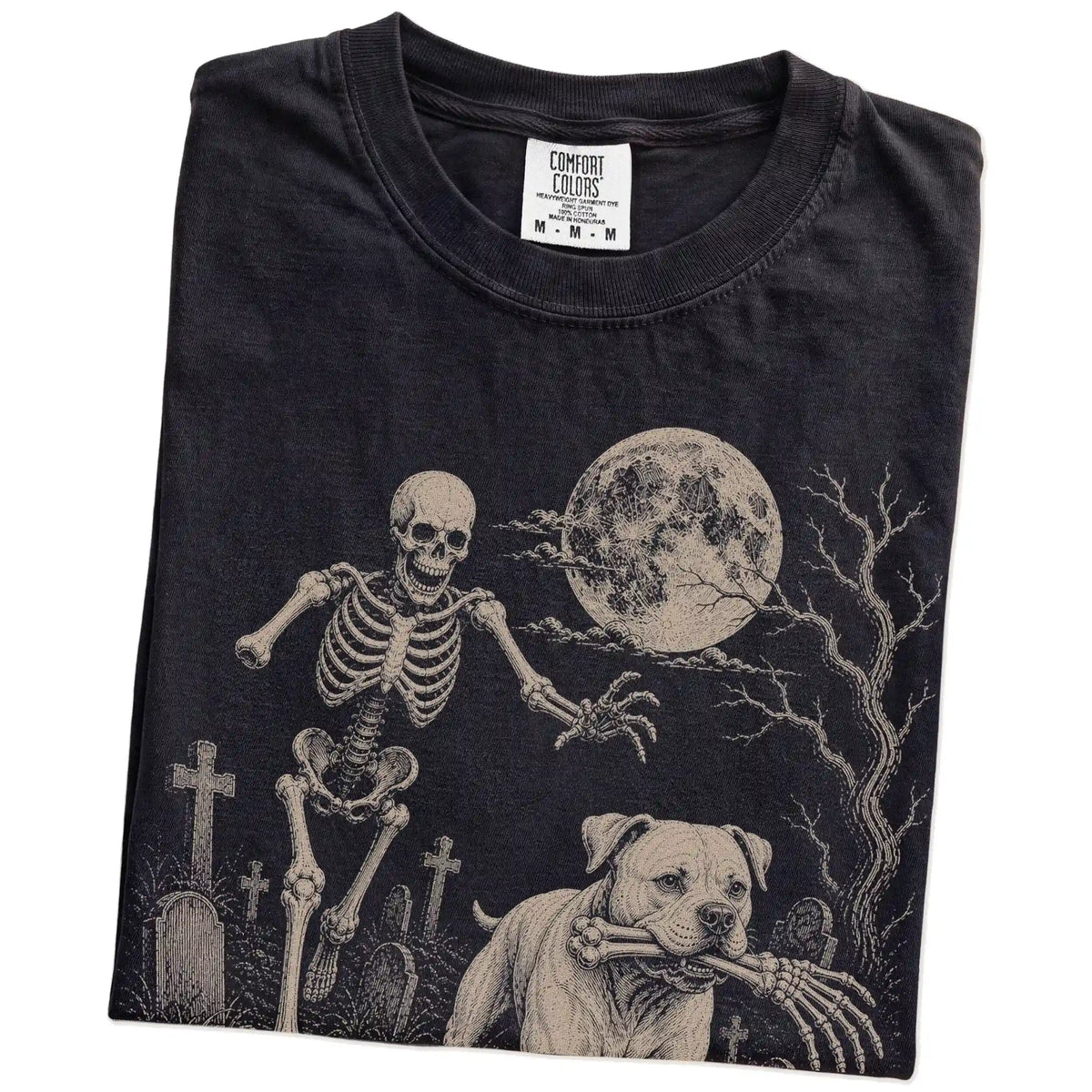 Folded Black Comfort Colors® T-shirt showing American Bulldog running through a moonlit graveyard with a chasing skeleton
