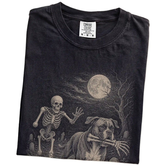 Folded Black Comfort Colors® T-shirt showing Boxer running through a moonlit graveyard with a chasing skeleton