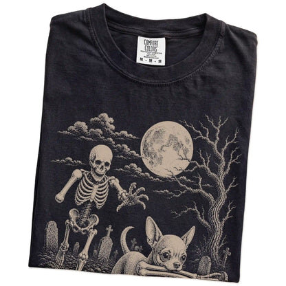Folded Black Comfort Colors® T-shirt showing Chihuahua running through a moonlit graveyard with a chasing skeleton