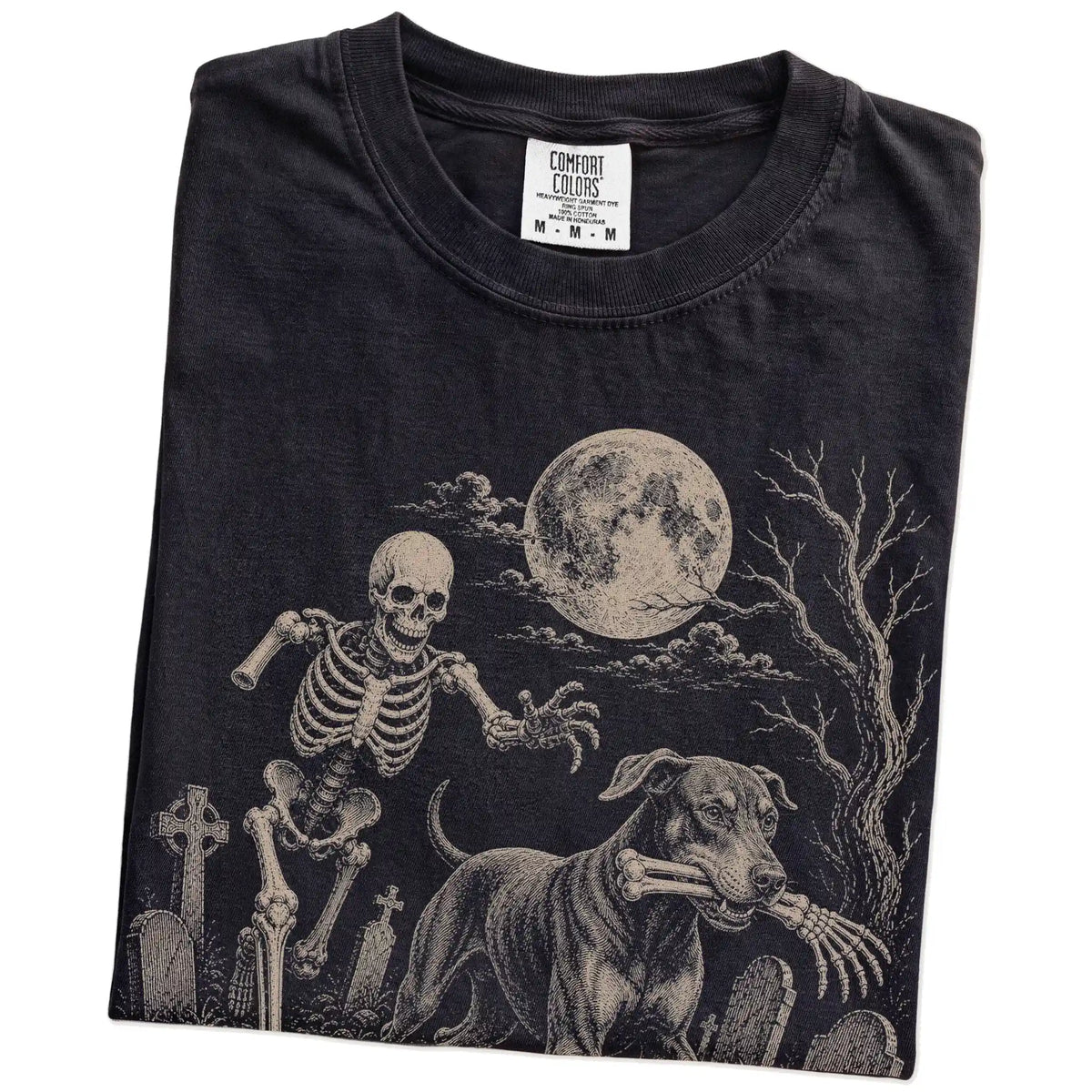 Folded Black Comfort Colors® T-shirt showing Doberman running through a moonlit graveyard with a chasing skeleton