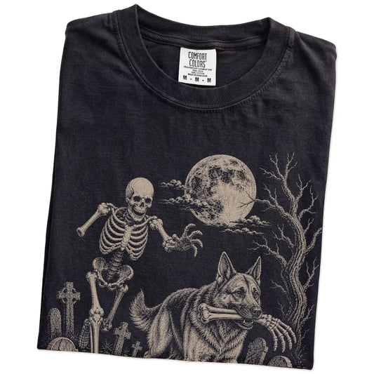 Folded Black Comfort Colors® T-shirt showing German Shepherd running through a moonlit graveyard with a chasing skeleton