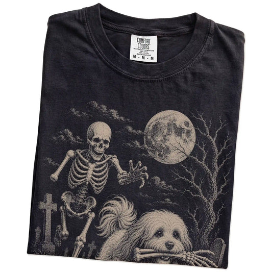 Folded Black Comfort Colors® T-shirt showing Havanese running through a moonlit graveyard with a chasing skeleton