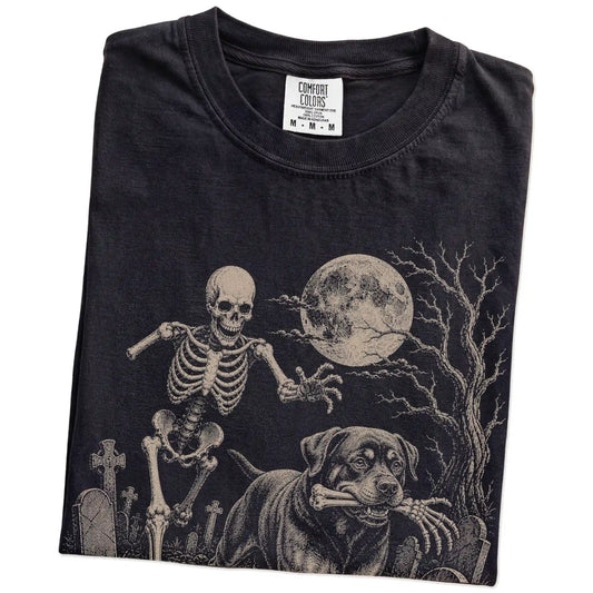 Folded Black Comfort Colors® T-shirt showing Rottweiler running through a moonlit graveyard with a chasing skeleton