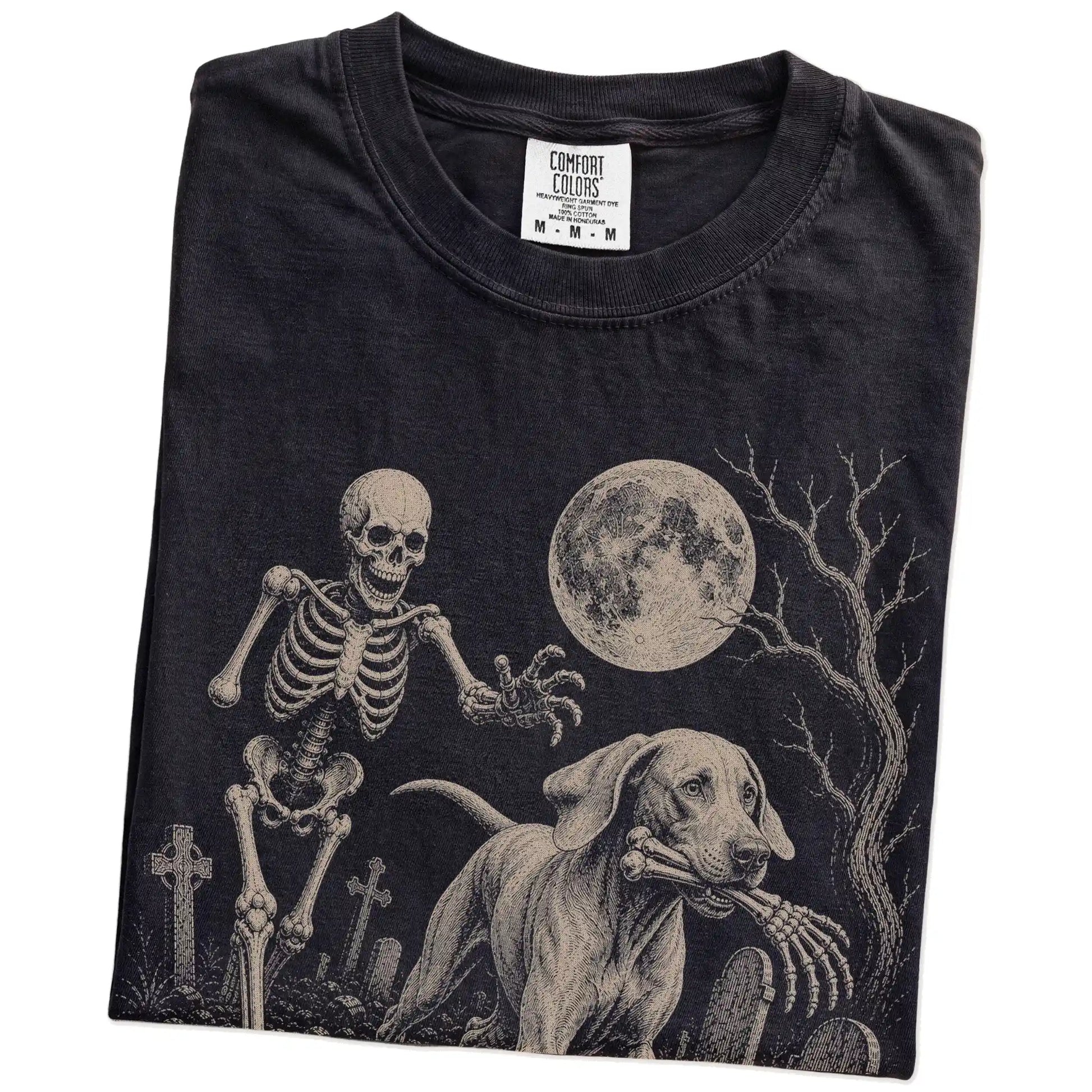 Folded Black Comfort Colors® T-shirt showing Weimaraner running through a moonlit graveyard with a chasing skeleton