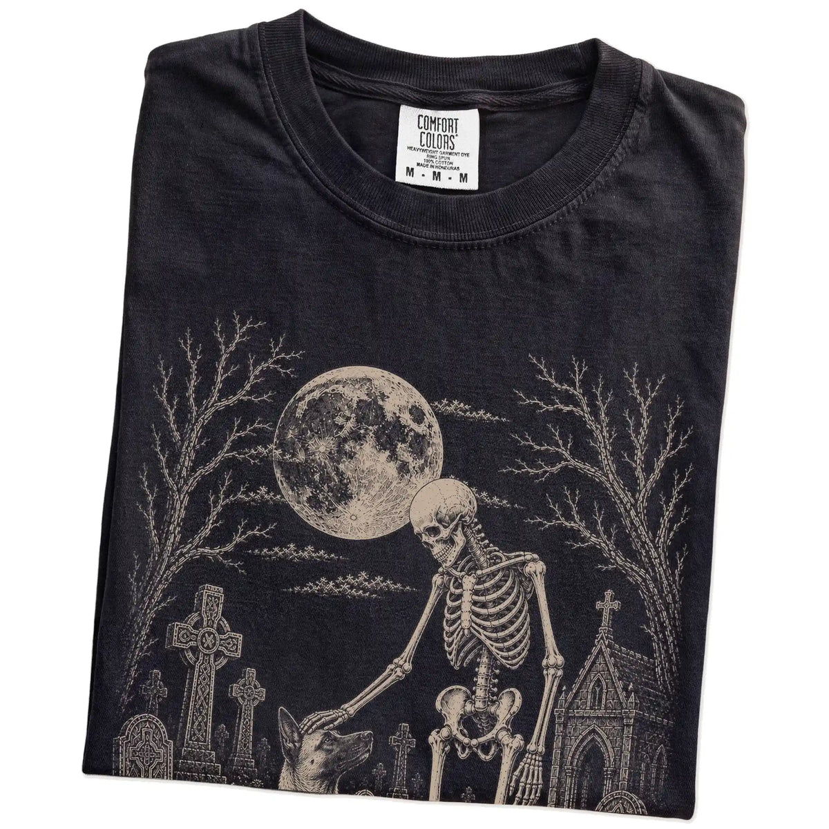 Folded Black Comfort Colors® T-shirt showing Belgian Malinois sharing a quiet cemetery moment with a friendly skeleton